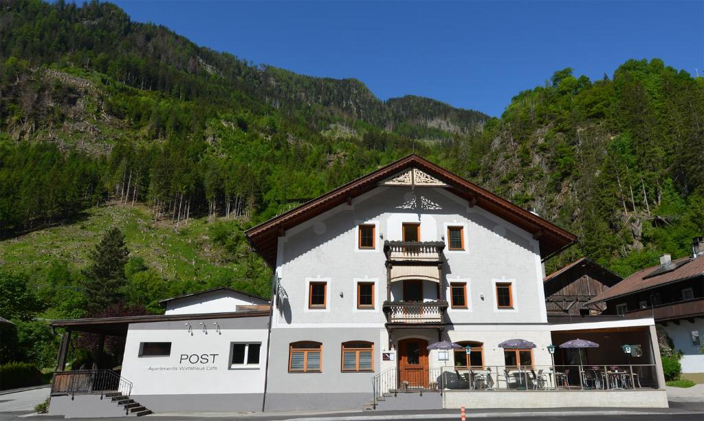 un grand bâtiment blanc en face d'une montagne dans l'établissement Gasthaus Post, à Matrei in Osttirol