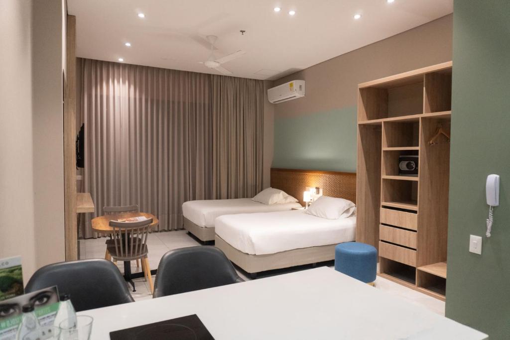伊瓦格的住宿－FR Hotel，酒店客房带两张床和一张桌子以及椅子。