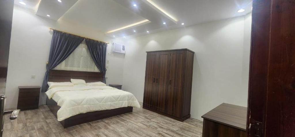 1 dormitorio con 1 cama grande y armario de madera en وحدات جنان en Ahad Rafidah