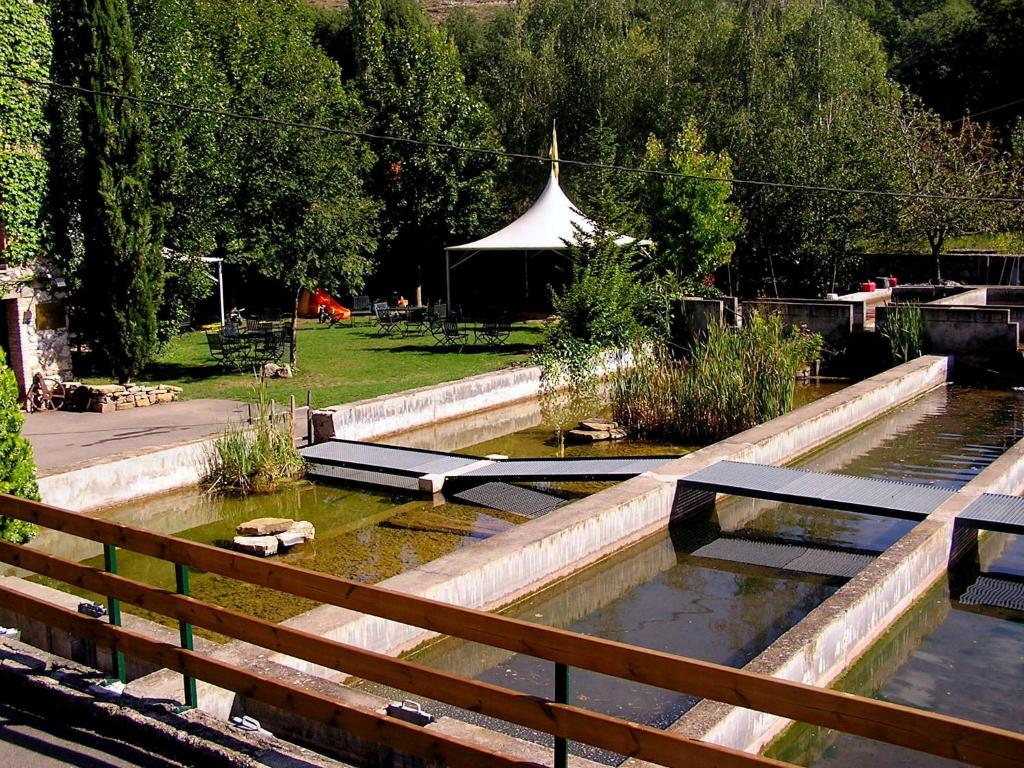 a pond in a garden with a tent in the background at La Fabrica Casa Rural in Senterada