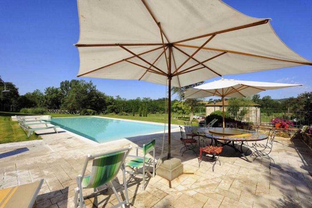 een patio met een tafel met een parasol en een zwembad bij Mulino della villa in Bucine