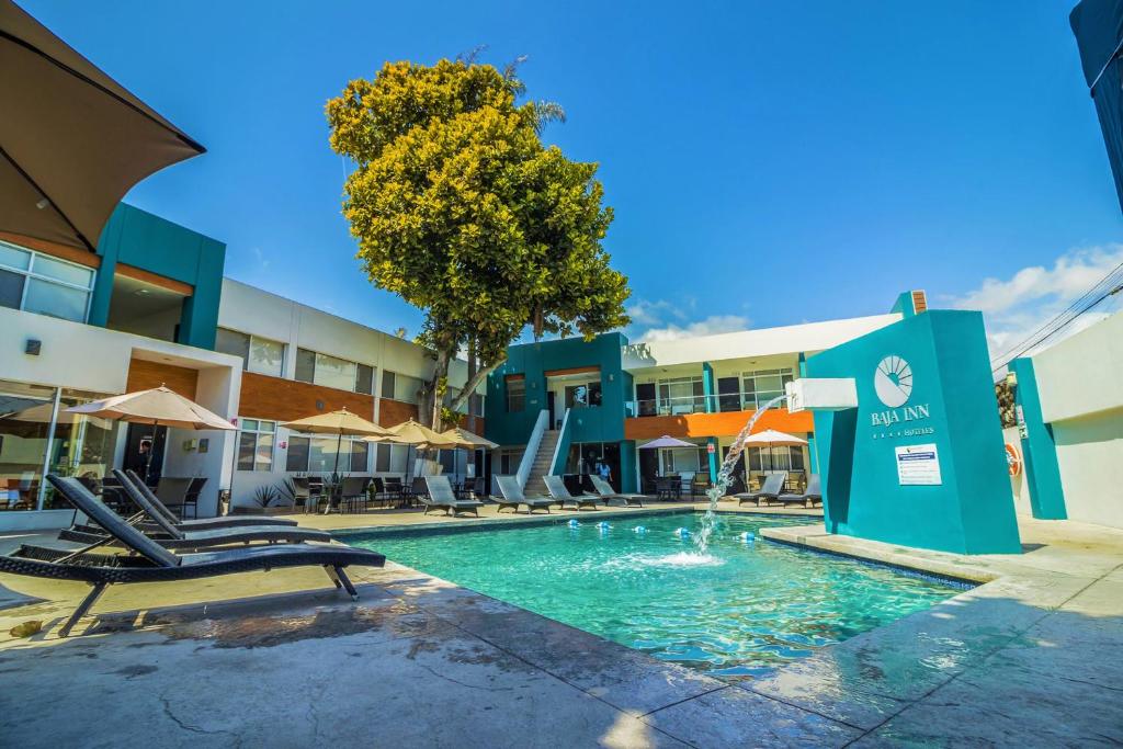 una piscina con sillas y sombrillas en un hotel en Baja Inn Hoteles Ensenada, en Ensenada