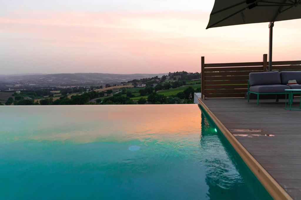 una piscina con 2 sillas y una sombrilla en una terraza en Villa meraviglia, en Collazzone