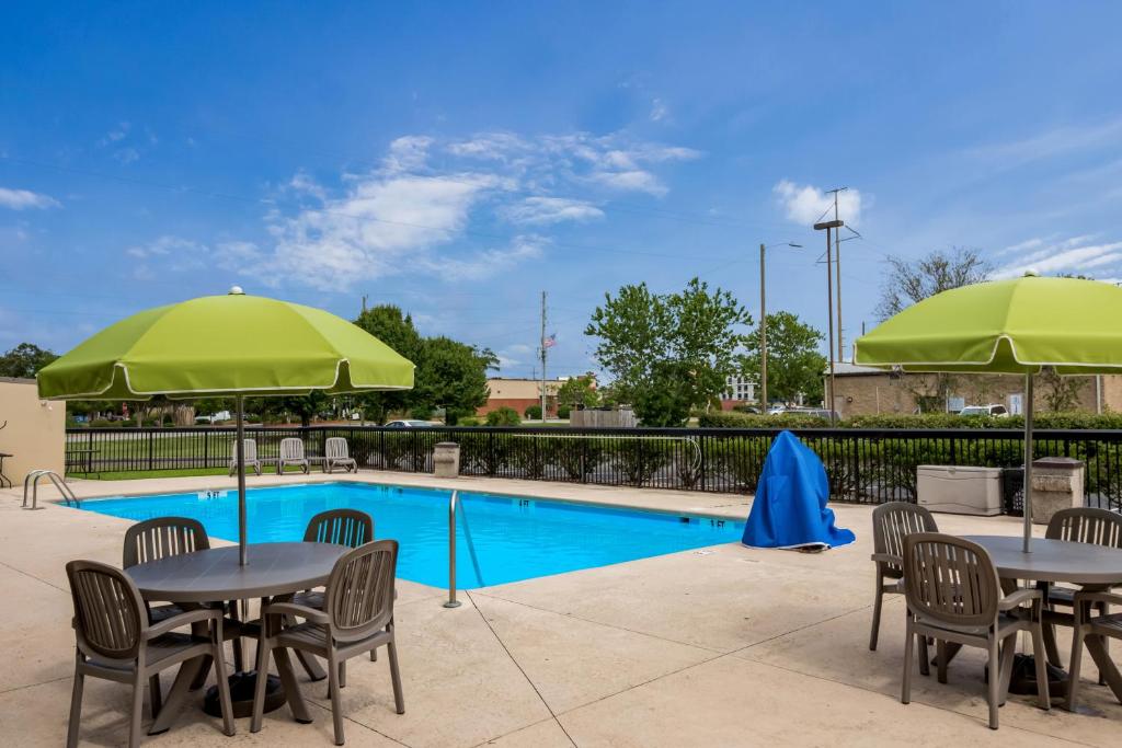 a pool with tables and chairs and green umbrellas at Red Roof Inn Wilmington NC in Wilmington