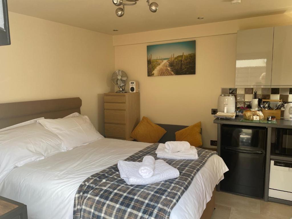 1 dormitorio con 1 cama con toallas en Auntie Bett's - Cosy double ensuite room with mini kitchen en Kingsbridge