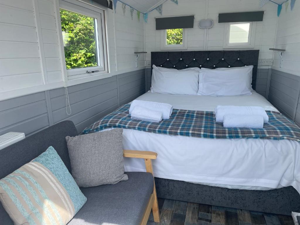 a small bedroom with a bed and a chair at Estuary View - Cosy Shepherds Hut in Kingsbridge