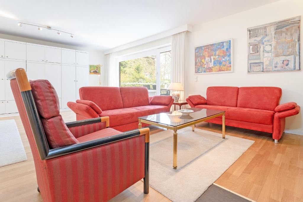 蒂門多爾費爾斯特蘭德的住宿－Haus Eva Mar am Meer Appartement 1，客厅配有2把红色椅子和桌子
