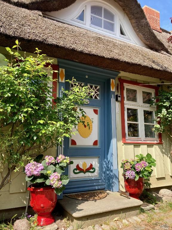 a small house with a blue door and flowers at Haus am Hafen - Luxus unter Reet, Garten, Strandkorb, kleine Idylle in Prerow