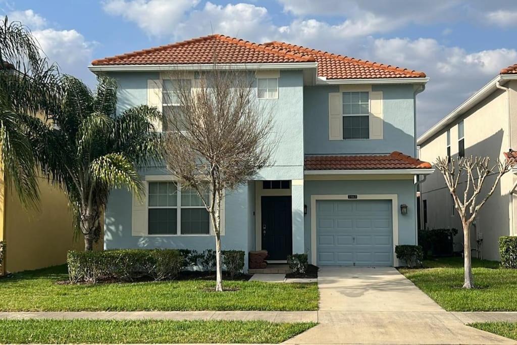 a blue house with a garage and palm trees at 6Br 6Bath Pvt Home Pool 10min Disney 3282ft in Kissimmee
