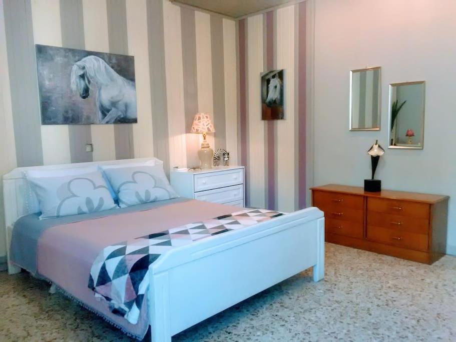 ein Schlafzimmer mit einem Bett und einer Kommode und einem Pferdegemälde in der Unterkunft Doxa's place in Iraklio