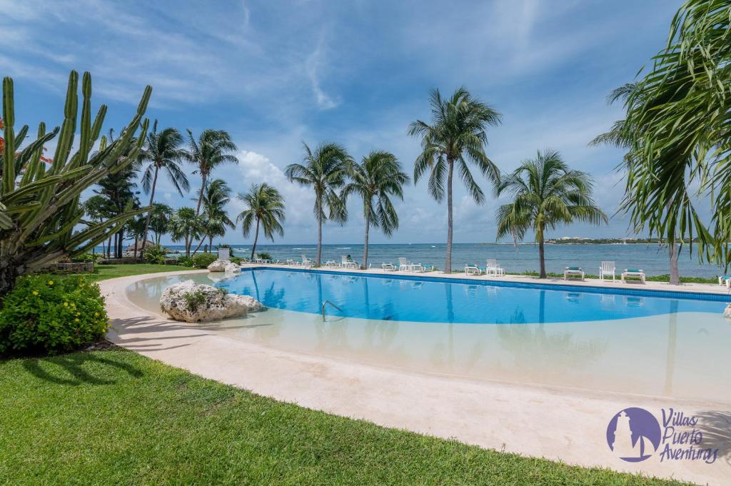 a swimming pool with the ocean in the background at Chac Hal, Beachfront Apartment with Amenities - Chac Hal 2 in Puerto Aventuras