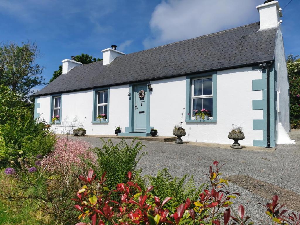 a white cottage with a blue door at New Listing - Ladybird Cottage - Donegal - Wild Atlantic Way in Donegal