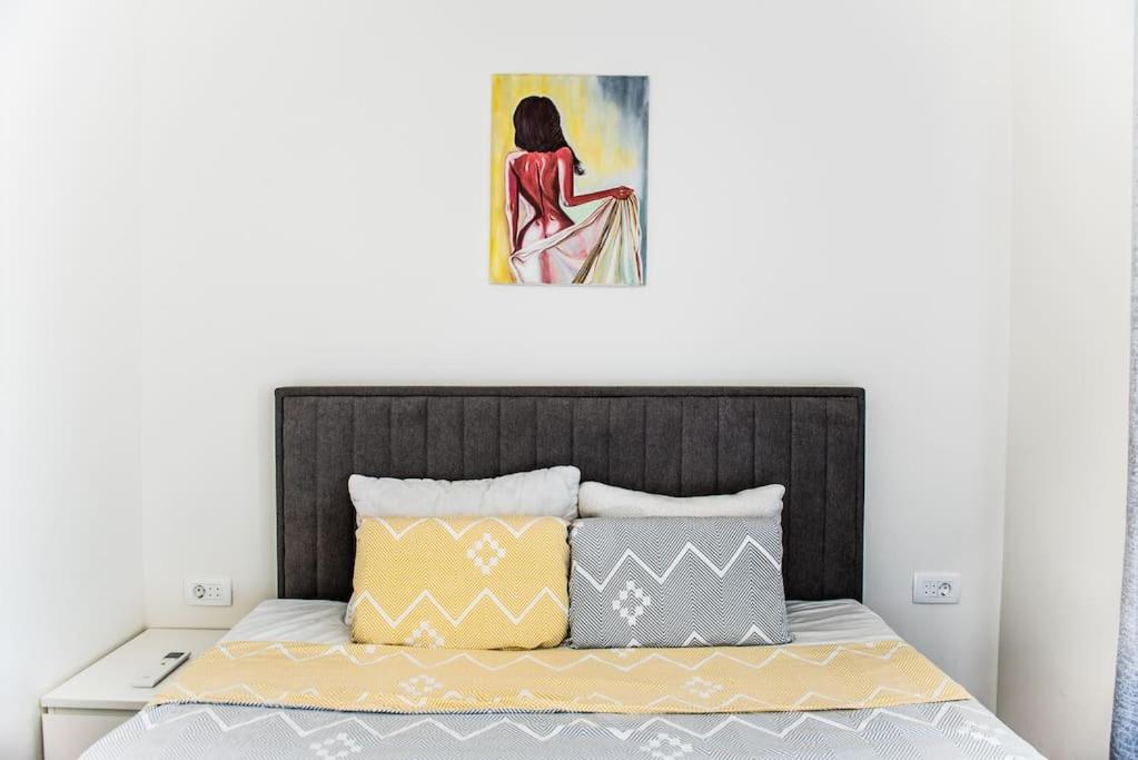 una cama con almohadas amarillas y grises y una pintura en Apartment with a sea view., en Tivat