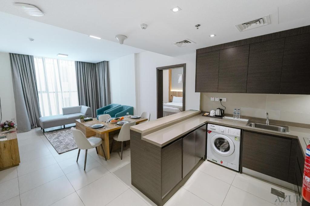 a kitchen and living room with a table and a dishwasher at Azur Regency Hotel Apartments in Dubai