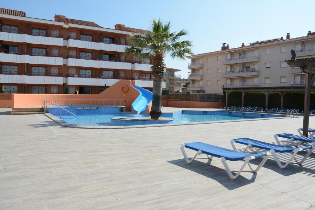 una piscina con 2 sillas azules y un tobogán en Apartamentos familiares Sa Gavina Gaudí, en L'Estartit