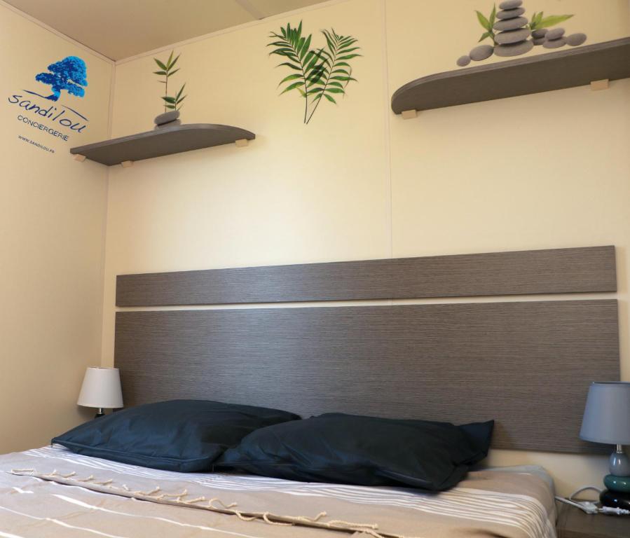 a bedroom with a bed with a wooden headboard at Mobilhome Côté mer - 3 Chambres - Climatisé - TV in Sigean