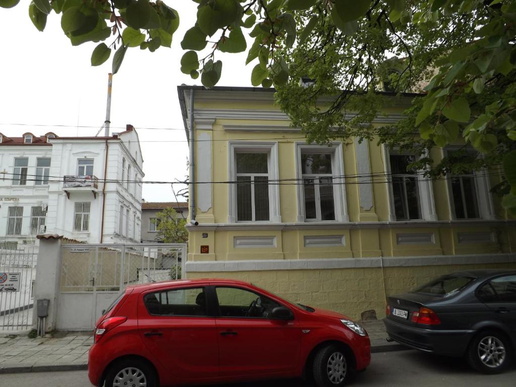 a red car parked in front of a yellow building at Hostel Rayska Yabalka in Varna City