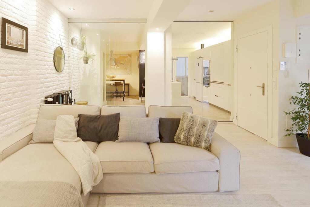 ein weißes Wohnzimmer mit einem Sofa und einer Küche in der Unterkunft 186A Magnífico Apto en La Arena in Gijón