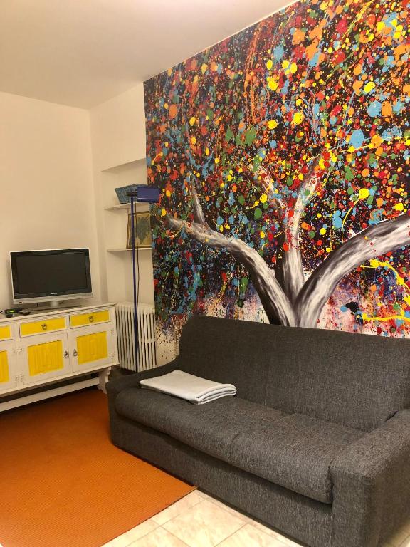 un salon avec un canapé et une peinture d'un arbre dans l'établissement L’Albero Colorato, à Candelo