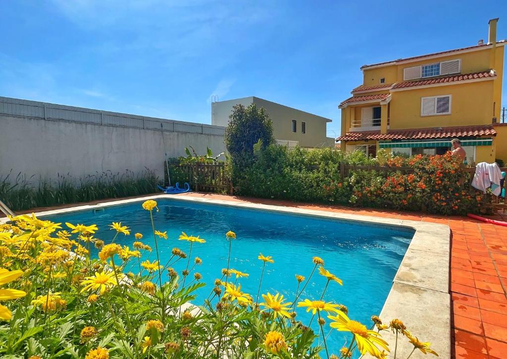 uma piscina em frente a uma casa com flores amarelas em Oceans house - Pool, Sauna, 22 Sleeps, 7m to beach em Carcavelos