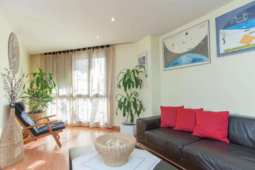 een woonkamer met een zwarte leren bank en rode kussens bij Marina in Barcelona