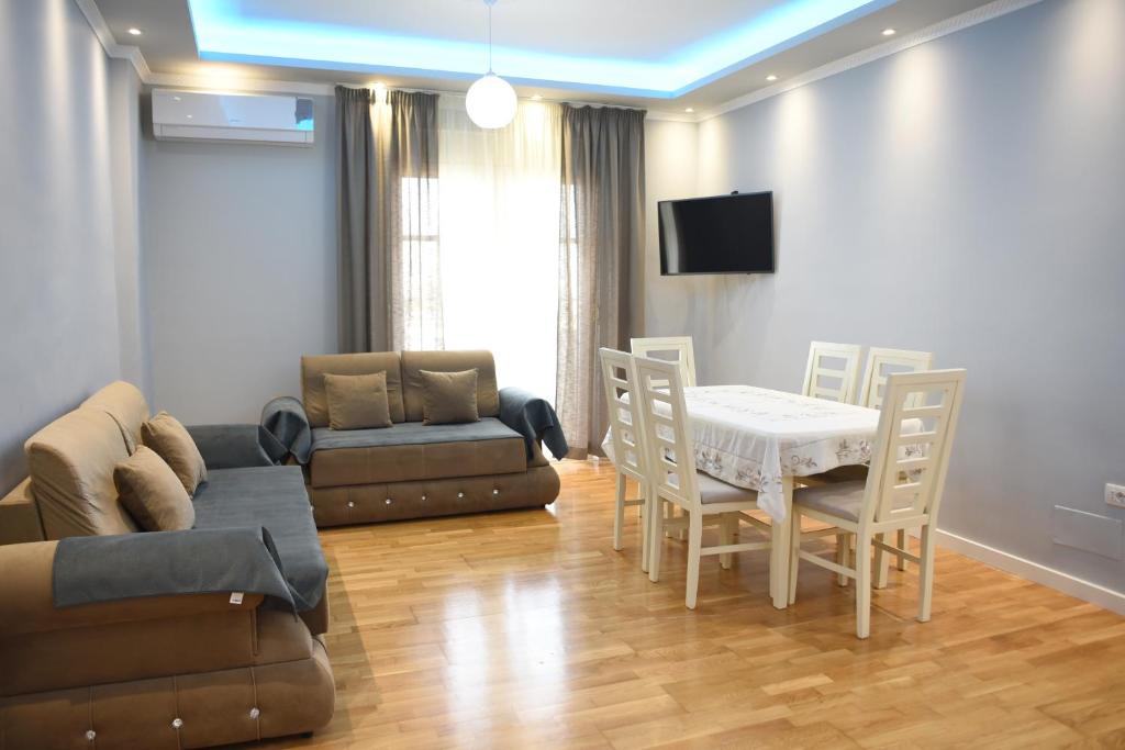 uma sala de estar com um sofá, uma mesa e cadeiras em Durres Luxury Beach Apartment em Durrës