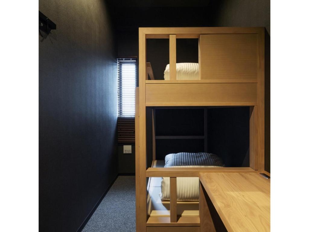 9 C Hotel Asahikawa - Vacation STAY 58446v في اساهيكاو: سرير بطابقين خشبي في الغرفة