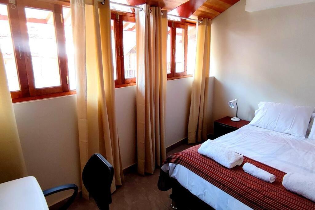 a bedroom with a bed and two windows at Departamento privado cerca a la plaza in Pisac