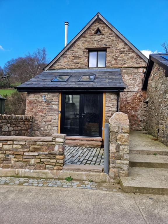 een stenen huis met een veranda en een raam bij The Old Pig Sty in Llanellen