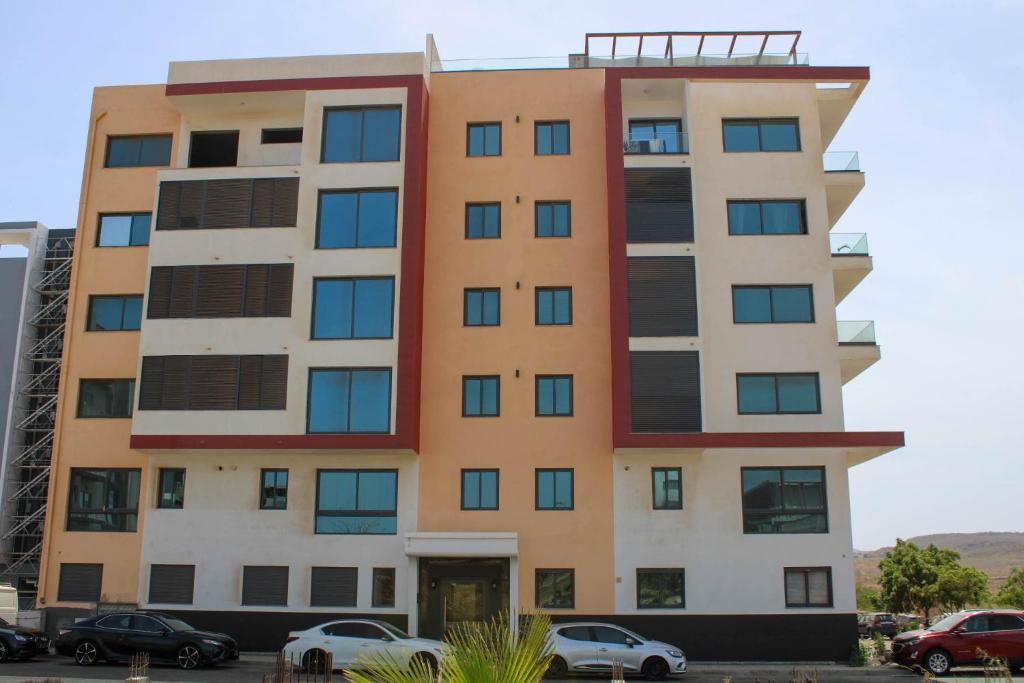 un edificio alto con coches estacionados frente a él en Apartamento JL en Praia