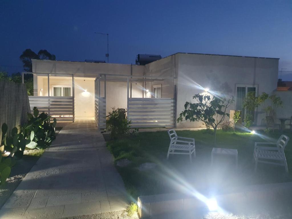 une maison blanche avec deux chaises blanches dans la cour la nuit dans l'établissement SeA Beach Home, à Torre Lapillo