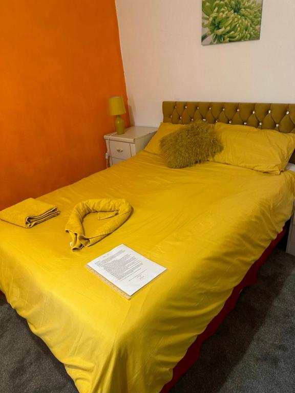 Una cama con sábanas amarillas y un teléfono. en Quick Stop Night Stay - Gatwick, en Crawley