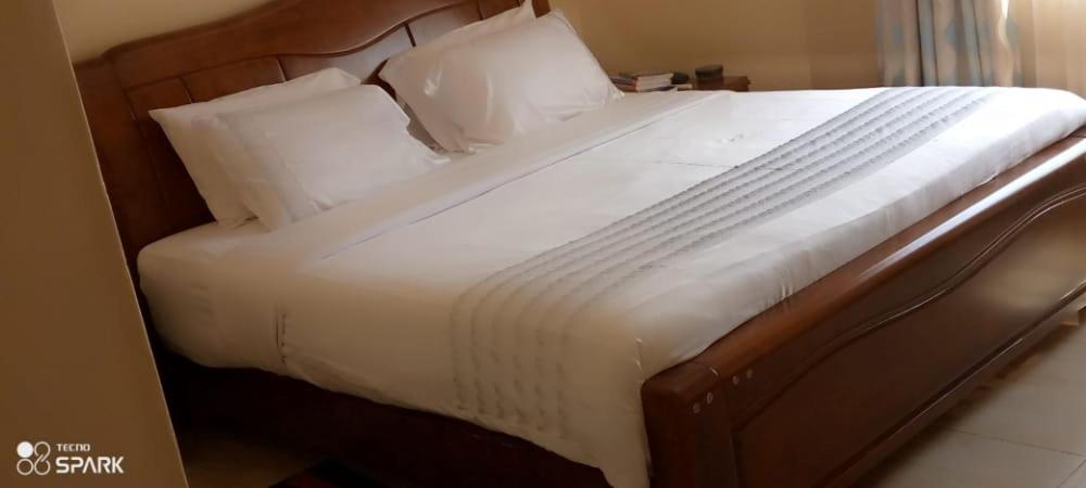 a large bed with white sheets and pillows at Stream Box Lodge in Lilongwe