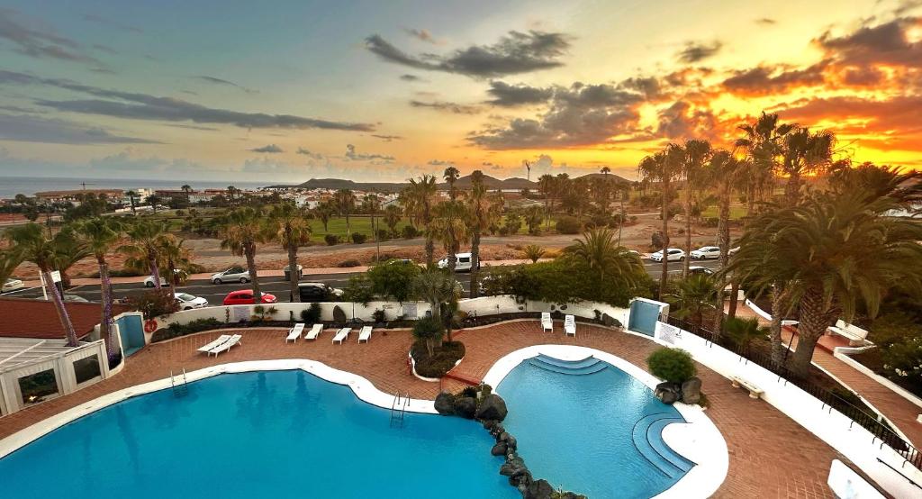 - une vue sur la piscine d'un complexe avec un coucher de soleil dans l'établissement Suite Poseidon Golf & Ocean View, à San Miguel de Abona