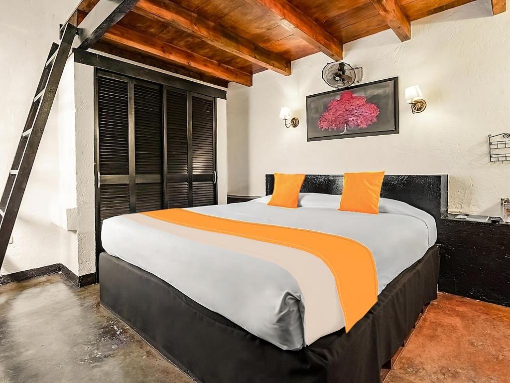 1 dormitorio con 1 cama grande con almohadas de color naranja en Calesa Real en Querétaro