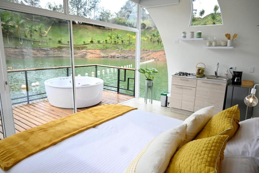 ein Schlafzimmer mit einer Badewanne und einem großen Fenster in der Unterkunft Casa Flotante La Trinidad in Guatapé