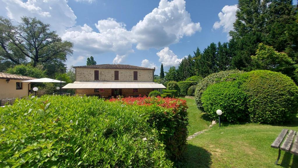 um jardim com um edifício e alguns arbustos e flores em Country Hotel Poggiomanente em Umbertide
