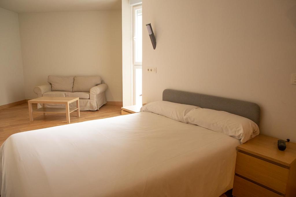 a bedroom with a white bed and a couch at Apartamentos Lidar in Bilbao