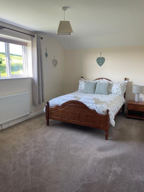 a bedroom with a bed and a window at Little Stone Farm Cottage in South Molton