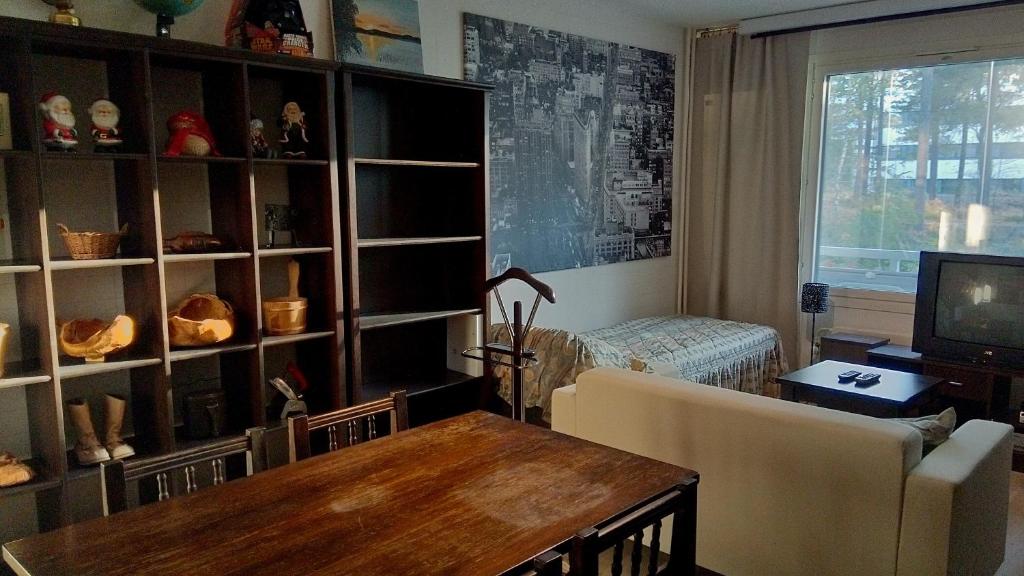 a living room with a table and a couch and a television at 21 minutes from Helsinki city - larger room in Kauniainen