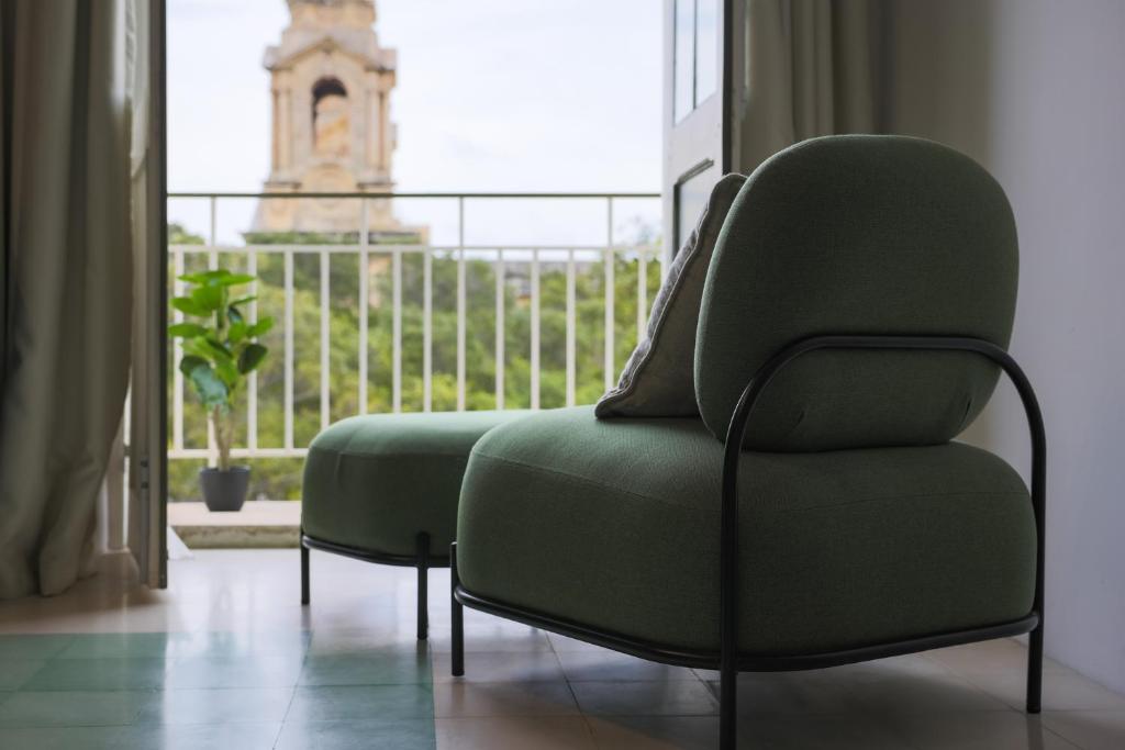 einem grünen Stuhl vor einem Fenster in der Unterkunft Stylish Apartment steps from the Capital in Floriana