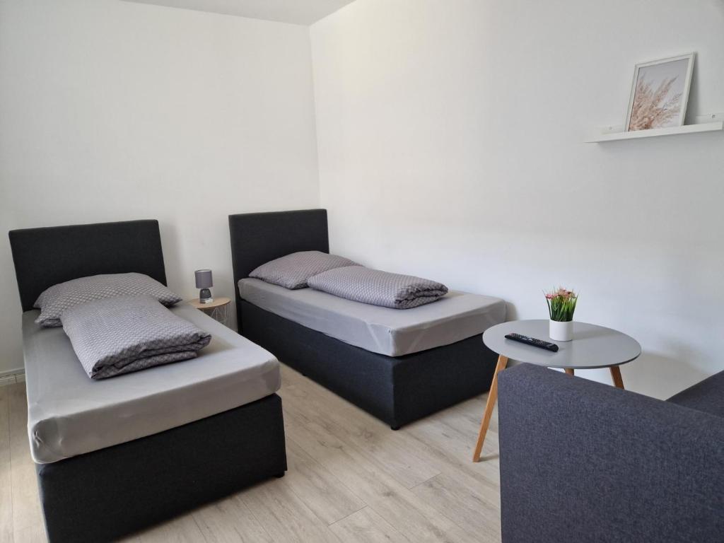 2 Betten in einem Zimmer mit einem Tisch und einem Sofa in der Unterkunft Nordunterkunft in Neumünster