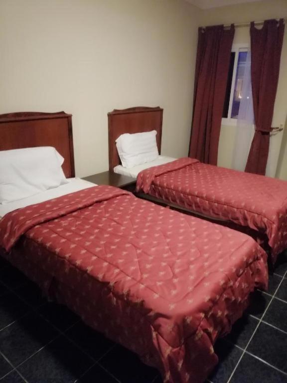 two beds with red covers in a room at مزايا هاوس in Dammam