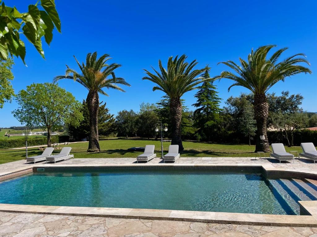 - une piscine bordée de palmiers et de chaises longues dans l'établissement Mas Feliu Turismo Rural, à Pujals dels Cavallers