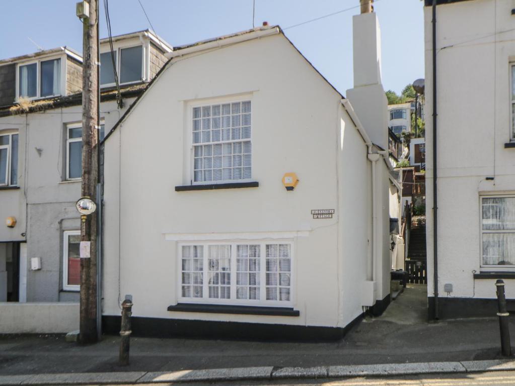 a white house on a street with buildings at Alexandra Cottage in Looe