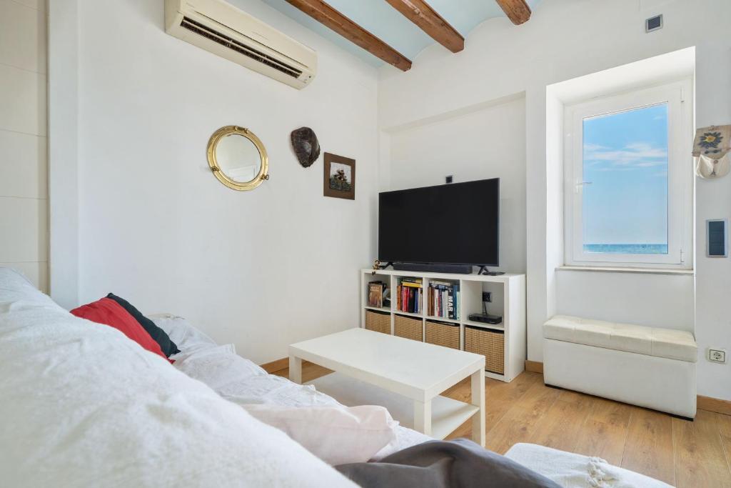 ein weißes Wohnzimmer mit einem TV und einem Sofa in der Unterkunft Voramar in Torredembarra