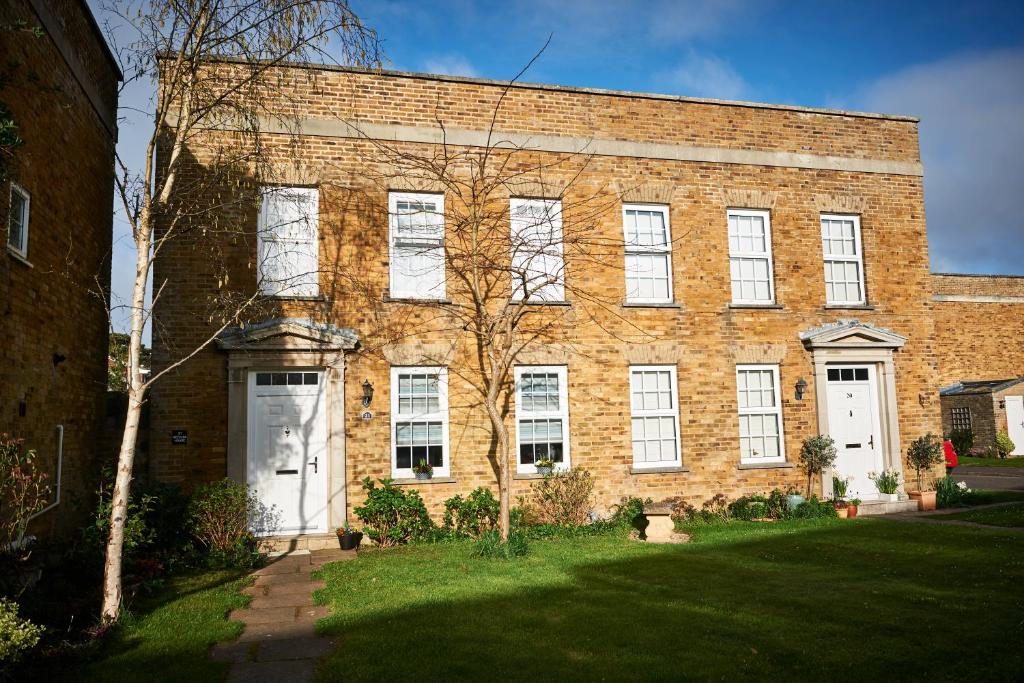 a large brick building with white doors and a yard at Needles House in Milford on Sea