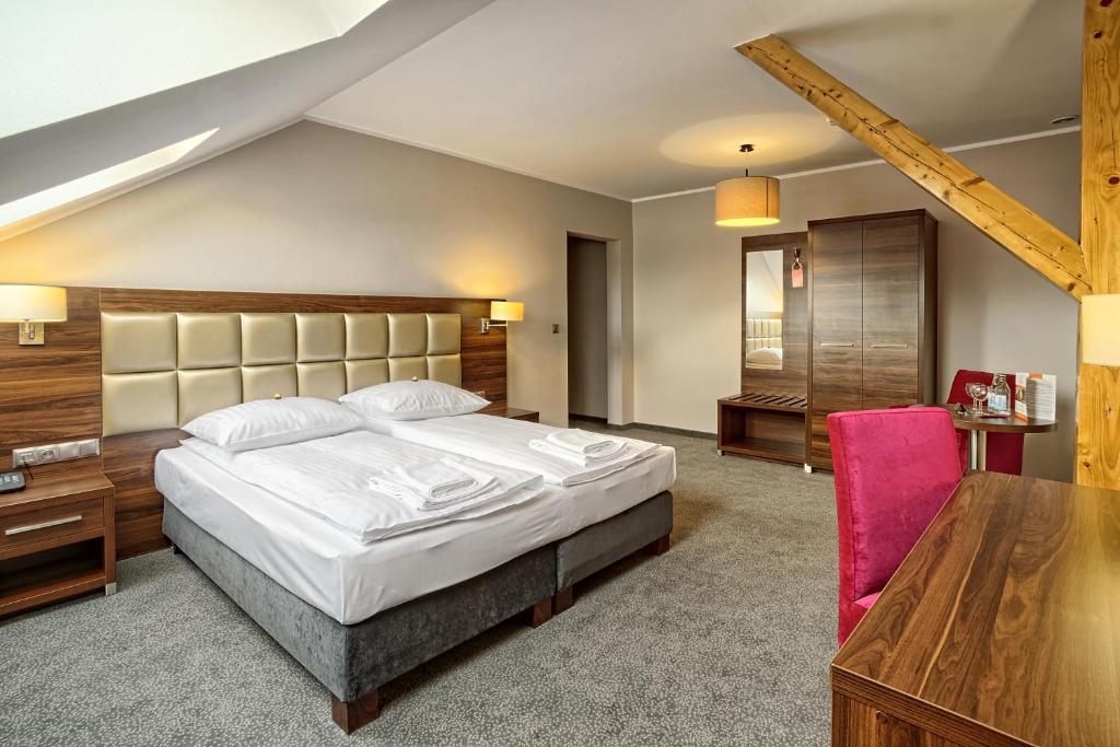 a bedroom with a large bed and a wooden table at Hotel Kamieniczka in Legnica