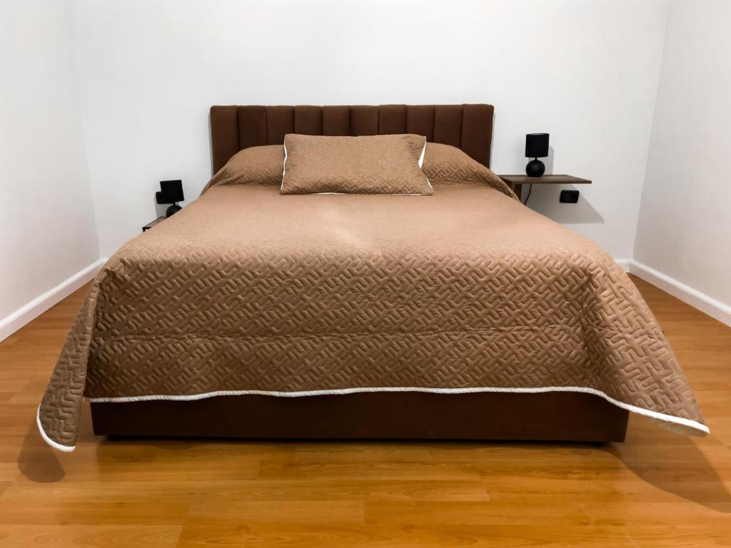 a bed in a white room with a brown blanket at Vila Kodra in Tirana
