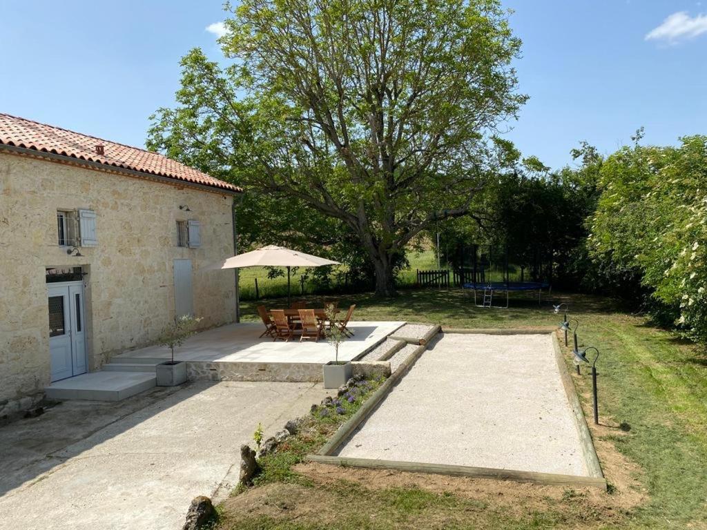 a garden with a table and chairs and a building at Les figuiers de Jeanne in Castelculier